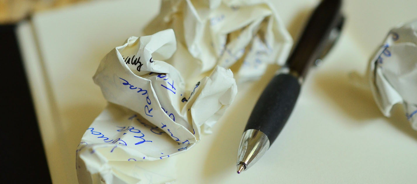 Image of crumpled paper and a pen lying on blank paper